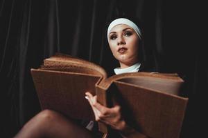Beautiful young nun in religion black suit holds Bible. Religion