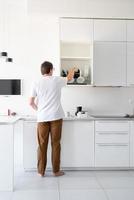 Hombre de camiseta blanca lavando platos en la cocina foto