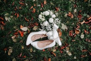 wedding bouquet of white roses and high-heeled shoes on a green grass photo