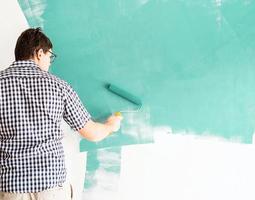 Hombre coloreando la pared verde con un rodillo foto