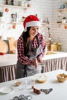 Young latin woman pouring flour to the dough cooking at the kitchen photo