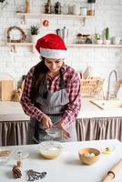 Young latin woman pouring flour to the dough cooking at the kitchen photo