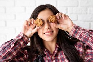 Mujer feliz en delantal sosteniendo galletas en forma de estrella delante de sus ojos foto