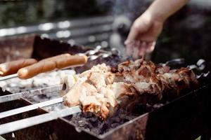 Cerca de kebabs en brochetas, hombre asando carne al aire libre foto