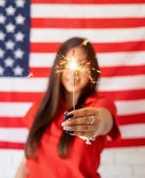 Bella mujer sosteniendo una bengala en el fondo de la bandera estadounidense foto