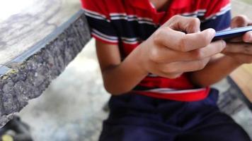 mão de câmera lenta de menino asiático usando smartphone. movimento de tiro pan. video