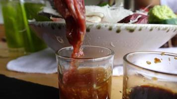 Zeitlupe Nahaufnahme Hand mit Essstäbchen, um Fleisch in Sesam zu legen video
