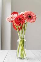 Bright gerbera daisies in white vase on table photo