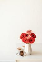 Bright gerbera daisies in white vase on kitchen table, minimal style