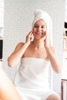 Happy laughing young woman doing morning make up looking at the mirror