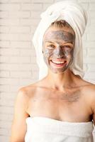 Happy smiling woman wearing white bath towels with a facial mask photo