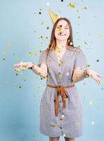 Tennager girl blowing confetti over blue background photo