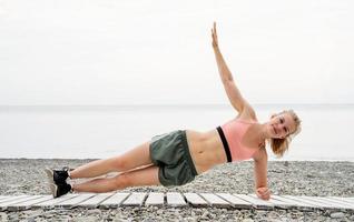 mujer atleta blong haciendo ejercicios en la playa foto
