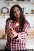 mujer con una bengala celebrando la navidad en la cocina foto