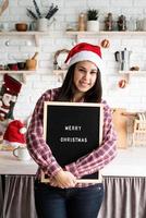 Mujer con gorro de Papá Noel con tablero de letras negro foto