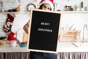 Mujer con gorro de Papá Noel con tablero de letras negro foto