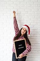 Mujer con gorro de Papá Noel con tablero de letras negro foto