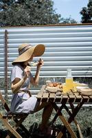 Mujer sentada a la mesa, comiendo verduras asadas al aire libre foto