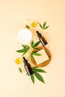 Cbd oil and cannabis leaves cosmetics top view on orange background photo
