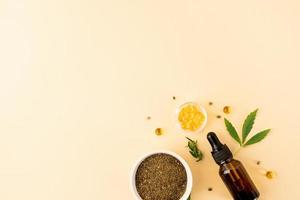 Cbd oil and cannabis leaves cosmetics top view on orange background photo