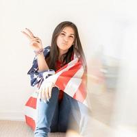 Hermosa mujer joven con bandera americana sobre fondo blanco. foto