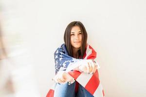 Hermosa mujer joven con bandera americana sobre fondo blanco. foto