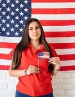 Mujer sosteniendo una pequeña bandera nacional en el fondo de la bandera de Estados Unidos foto