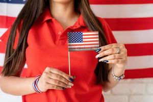 Mujer sosteniendo una pequeña bandera nacional en el fondo de la bandera de Estados Unidos foto