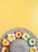 Summer hat with plumeria flowers on yellow background photo