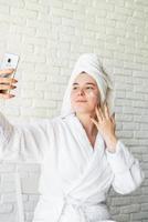 Woman applying face cream at home photo