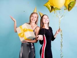 Mujeres sosteniendo globos celebrando un cumpleaños sobre fondo azul. foto