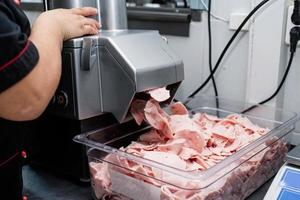 Woman is working on meat grinder machine photo
