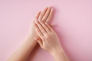 Beautiful female hands on pink background. Spa and body care concept. photo