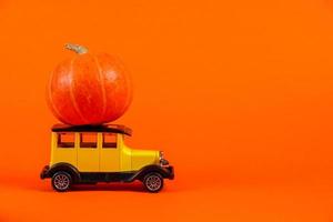 coche de juguete retro con una calabaza sobre un fondo naranja. foto