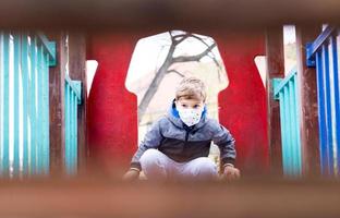 Little boy with kn95 face mask on the playground. photo