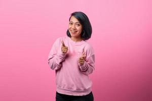 Cheerful young asian woman pointing fingers to camera