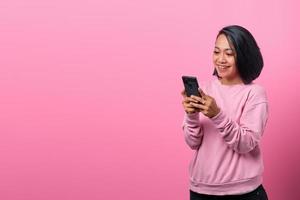 Cheerful young Asian using smartphone with smiling face photo