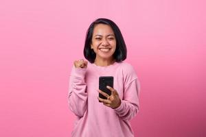 retrato, excitado, mujer joven, con, smartphone, en, fondo rosa