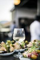 Copa de vino blanco con bocadillos de tapa de comida gourmet en el bar al aire libre al atardecer