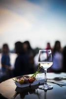 Glass of white wine with gourmet food tapa snacks in outdoors bar at sunset photo
