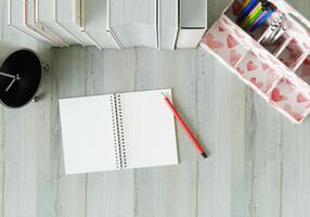 A working room with a notebook Pens and clocks on the white table. photo