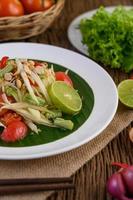 Papaya salad on a white plate on a wooden table photo