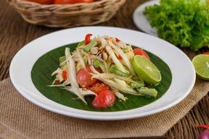 Papaya salad on a white plate on a wooden table photo