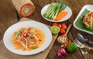 Papaya salad on a white plate on a wooden table photo