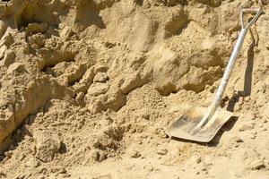Shovel on sand in construction site with copy space
