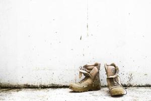 Old military boot on white wall background photo