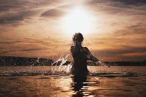 joven modelo nadando en el mar - hora del atardecer foto