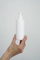 Hand hold blank white tube mock up isolated. Empty cream bottle mockup photo
