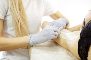 Waxing woman armpit with spatula. Salon wax beautician epilation photo