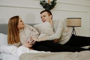Young couple in love is lying in bed, smiling and fooling around